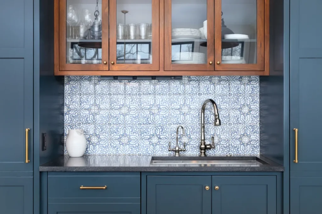 Blue kitchen cabinets with brass hardware and patterned tile backsplash